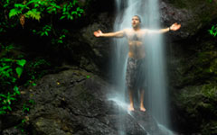 man standing under waterfall