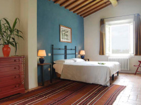 A bedroom in Brentina Est boasts wooden beams and warm blue walls