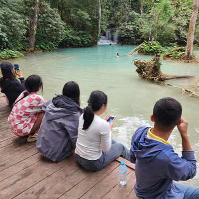 The children sit by the water